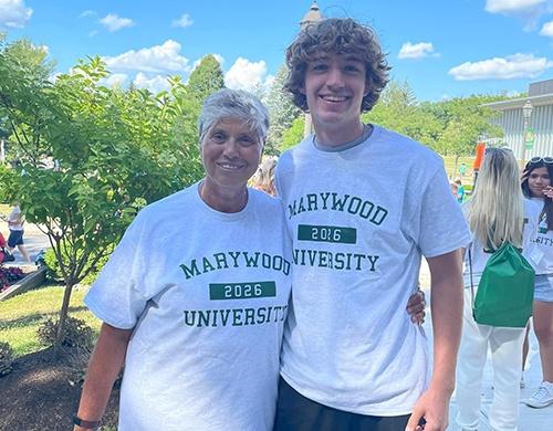 Young man and woman smiling wearing a matching marywood university t-shirt.