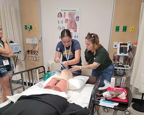 Two women practicing on a dummy for respiratory therapy