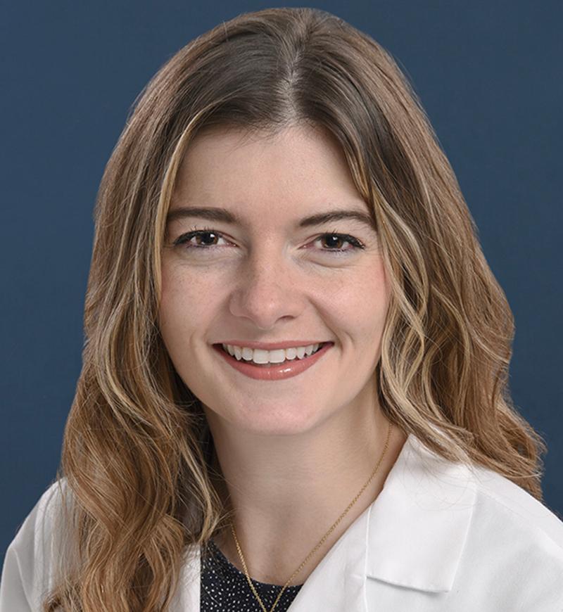 Headshot of a young woman smiling wearing a white coat.