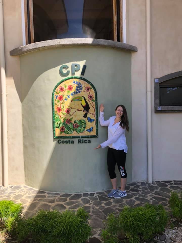 A young woman pointing to a Costa Rica sign.