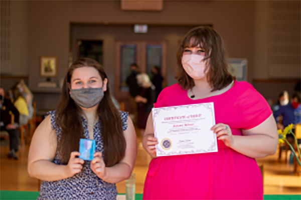 Two young women holding up awards.