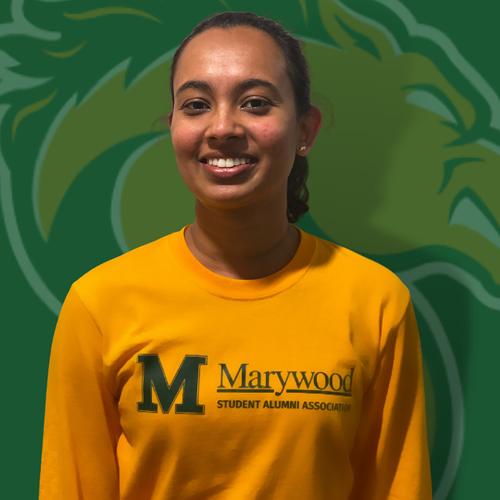 A smiling woman posing in front of a Marywood back drop.