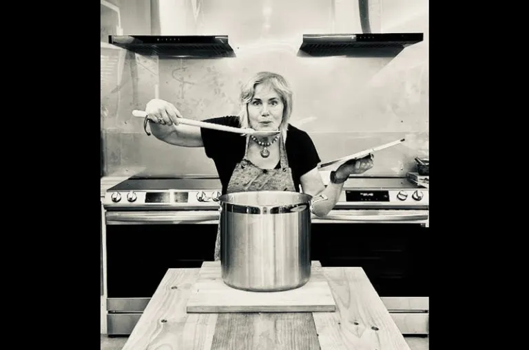 Keynote presenter Tannis Kowalchuk is picture over a large stockpot with a wooden spoon in her hand.