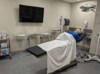 dummy laying on operating table with tools and tv in background