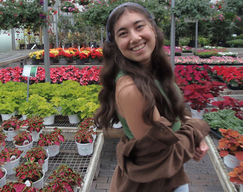 Young woman smiling with flower pots in the background