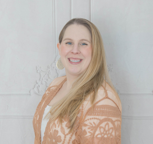 A woman standing against a stone wall.