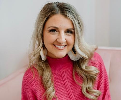 Young blonde woman smiling wearing a pink sweater