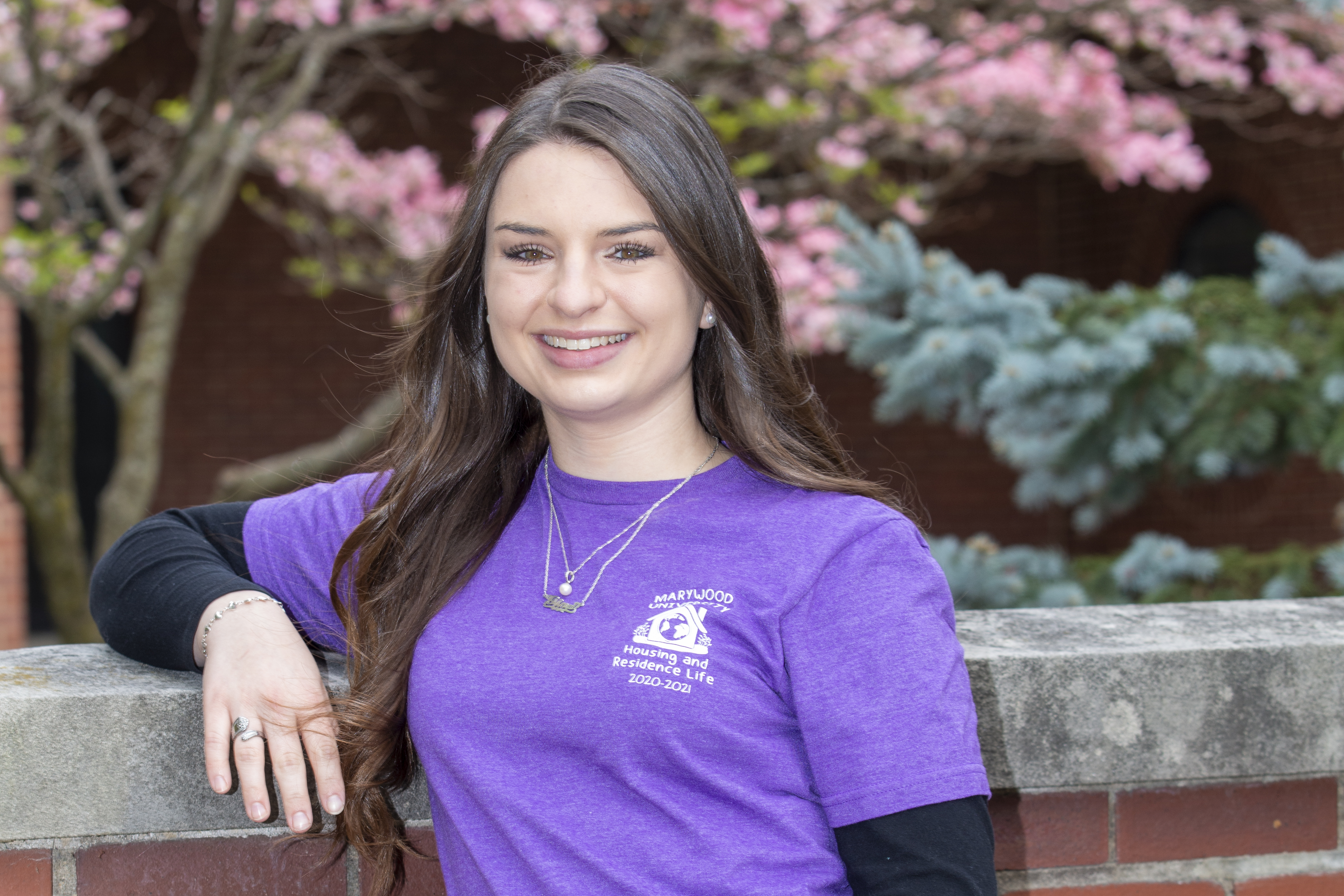 A young woman leaning on a brick wall.