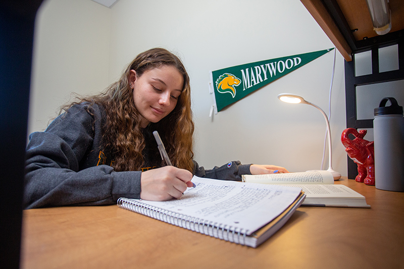 girl in dorm writing on notepad on desk