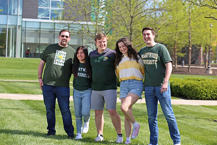 students smiling arm in arm wearing yellow and green in field